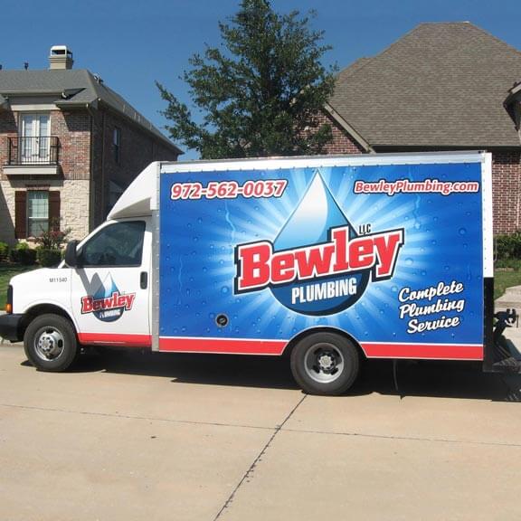 Bewley Plumbing box truck in front of a residential street with beautiful homes behind it.