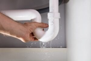 A man grabbing hold of a leaking pipe.