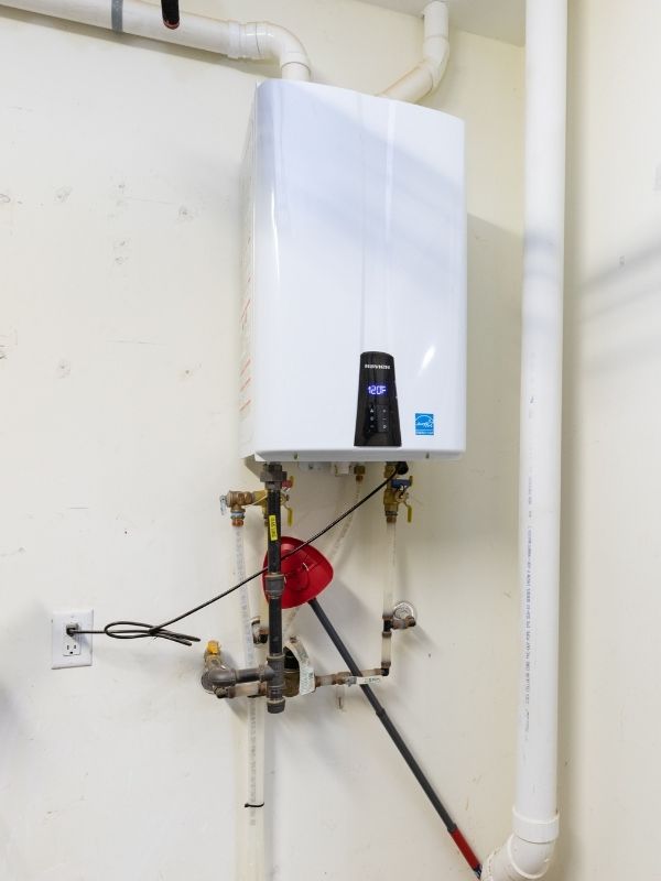 A tankless water heater is installed in the garage of a house.