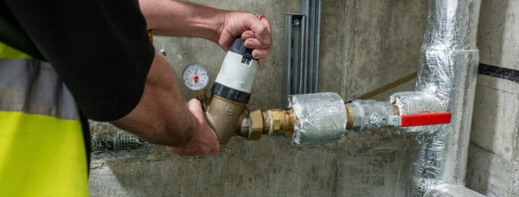 A plumber is working on commercial pipes.